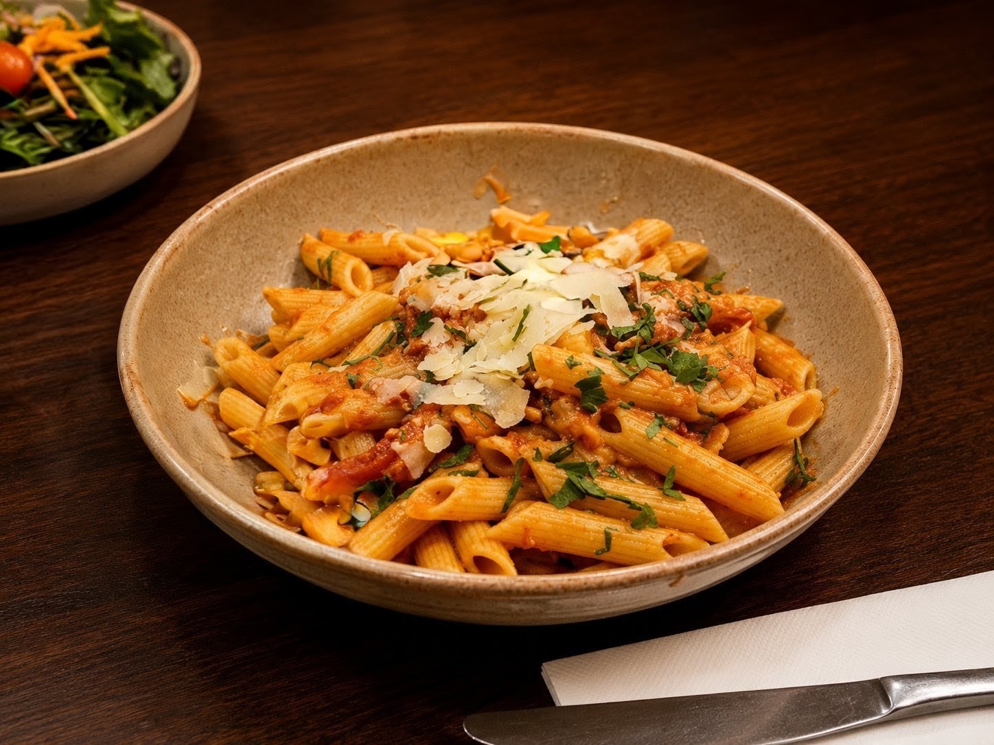 Penne pasta in rich tomato sauce with shaved parmesan