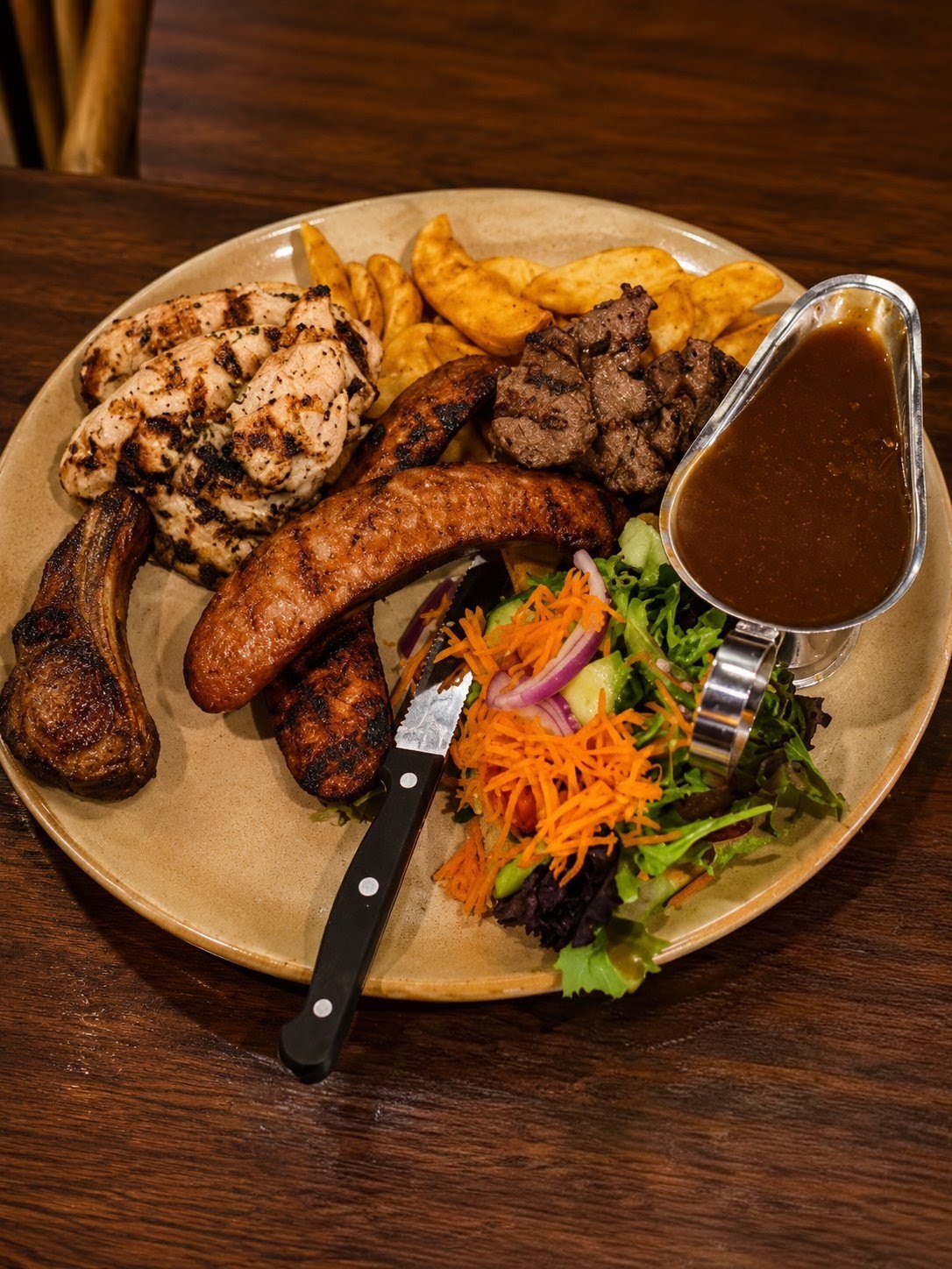 Mixed grill with chicken, sausage, lamb and steak, chips and salad